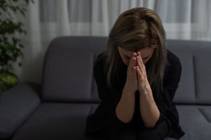 Woman Grieving Alone On A Couch, Symbolizing Emotional Pain Addressed Through Narrative Therapy And Grief Support