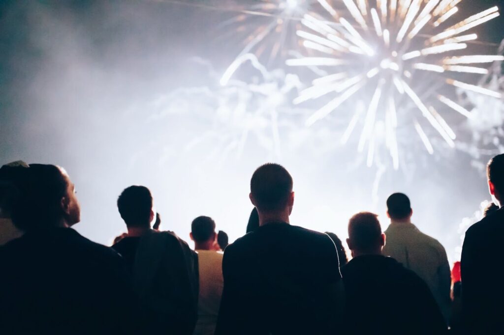 People Watching Fireworks During A Sober New Year's Eve Celebration, Standing Together Outdoors Under A Bright Night Sky.